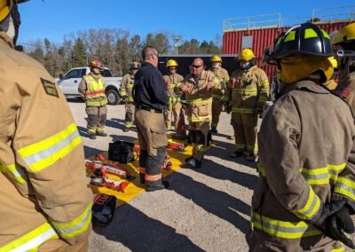 Firefighters in turnout gear gather around extrication tools during the class