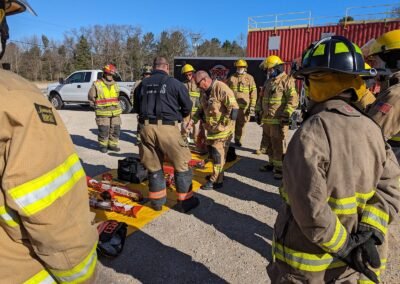 Firefighters in turnout gear gather around extrication tools during the class