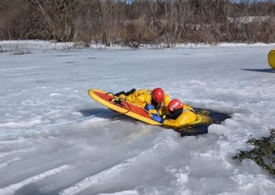 A rescuer on a rescue board works at the edge of the ice hole