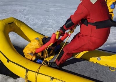 A rescuer helps pull a person into the inflatable rescue boat