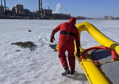 A rescuer pulls the inflatable rescue boat across the ice