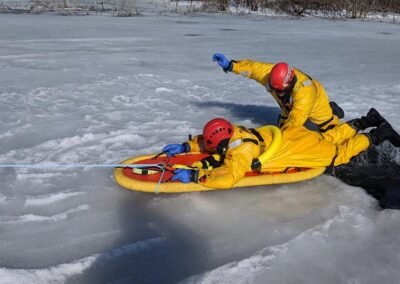 Rescuers pull a person onto a rescue board at the ice hole