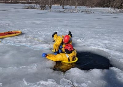 Two rescuers in the water at the hole in the ice