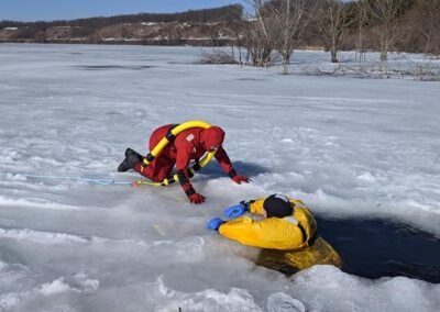 A rescuer reaches a person in the water from the ice