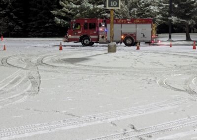 A fire engine working through the cone course in the snow at night, December 2, 2024