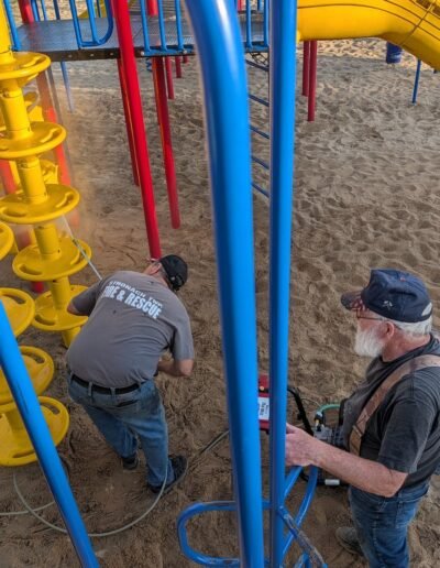 A member power-washes the playground equipment at Stronach Park
