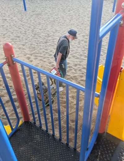 A member power-washes the playground equipment at Stronach Park