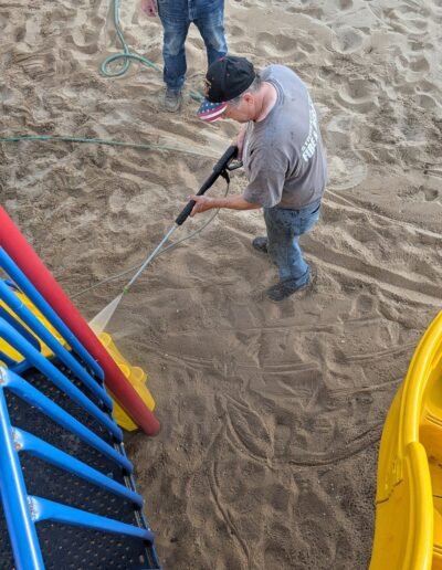 A member power-washes the playground equipment at Stronach Park