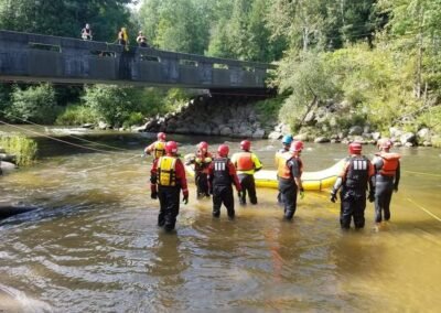 Class members wade into the river with the inflatable raft near a bridge