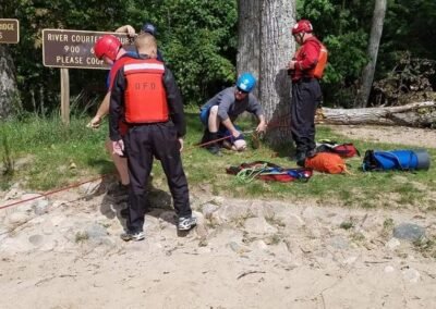 Students rigging rope lines beside the Pine River at Peterson Bridge during the swift water rescue class, September 2018