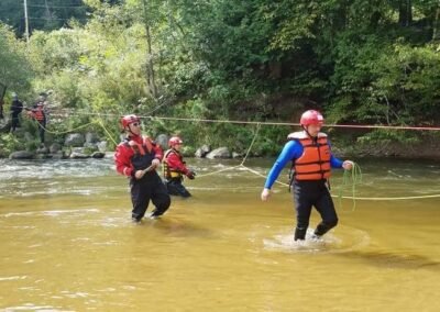 Students in helmets and life jackets wading the Pine River during the swift water rescue class, September 2018